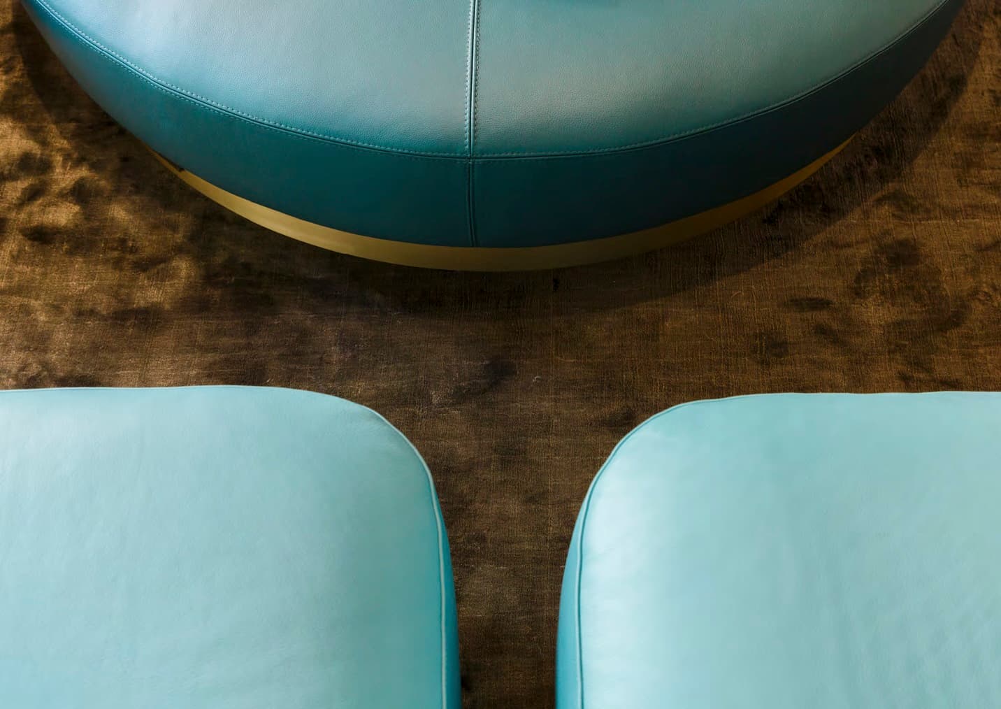 Light blue leather pouf on bronze rug